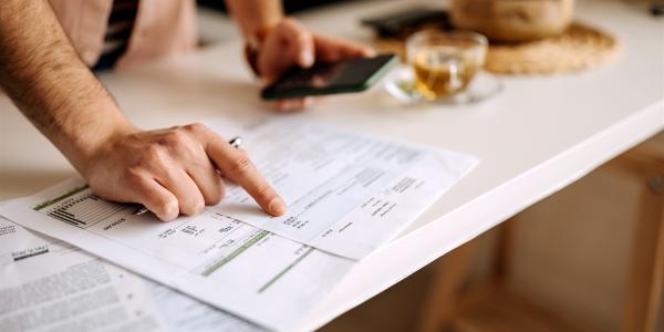 It depicts a person looking at papers laid out on a desk. 